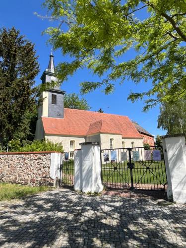 an old church with a gate and a tower at Remise an der Rennbahn - umzäuntes Anwesen mit Parkplätzen, AmzonPrime, Netflix, Wii, PS2 in Hoppegarten