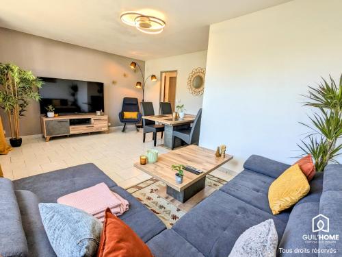 a living room with a blue couch and a table at Le Cocon - Lumineux - Grande TV - Parking gratuit in Fleury-les-Aubrais
