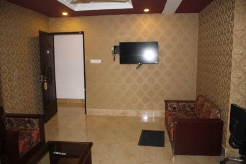 a room with a television on a wall with a couch at 78 Firoza Inn in Dhaka
