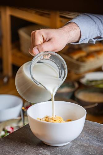 a person pouring milk into a bowl of food at DiliJazz Hotel & Restaurant in Dilijan