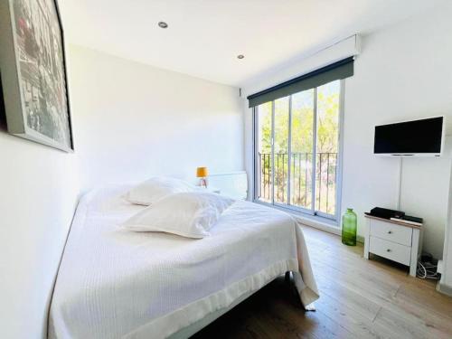 une chambre blanche avec un lit et une grande fenêtre dans l'établissement Studio, piscine, parking, à Saint-Tropez