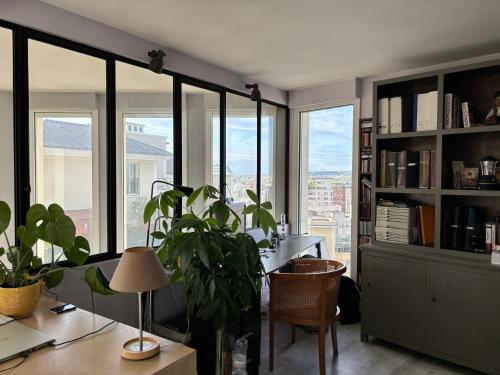 un bureau avec des fenêtres et un bureau avec une plante dans l'établissement Paris La Défense à 15min Champs Elysées - 140m2 avec terrasse 31m2 au dernier étage, à Courbevoie