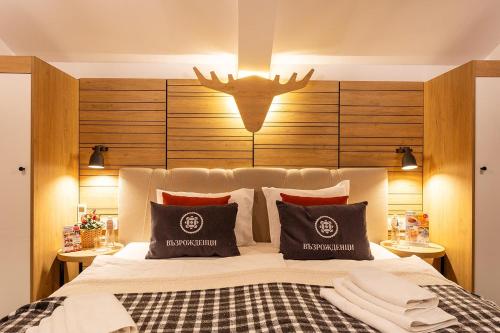 a bedroom with a large bed with a antler headboard at Complex Vazrozhdentsi in Tryavna