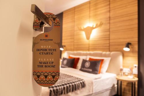 a room with a bed with a sign on the wall at Complex Vazrozhdentsi in Tryavna