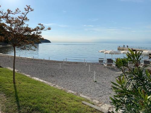 a beach with chairs and an umbrella and the water at Lavanda Apartment in Izola