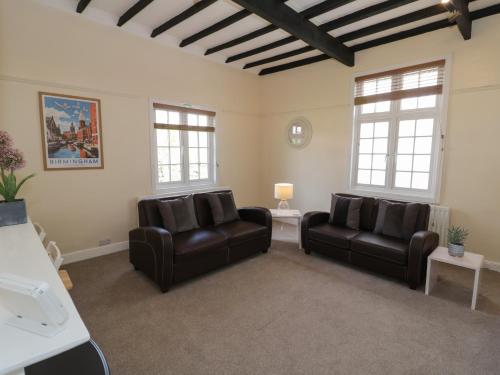 a living room with two leather chairs and two windows at Above The Pub in Birmingham