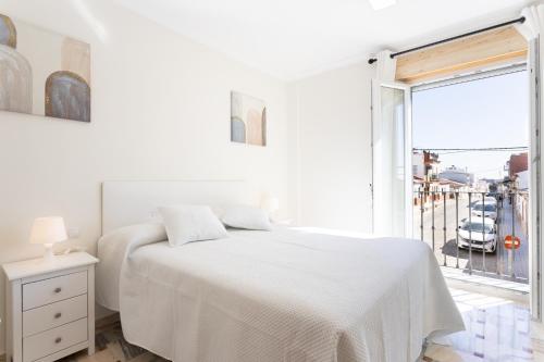 una camera bianca con un letto e una grande finestra di La posada de Itálica a Santiponce