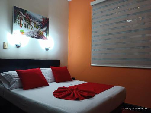um quarto com uma cama com almofadas vermelhas e uma janela em Hotel La Herreria Colonial em Popayán