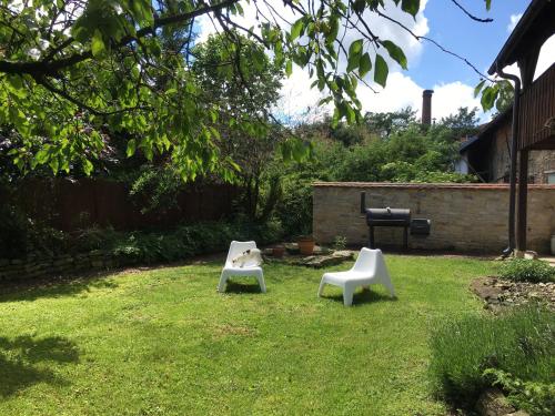two white chairs sitting in the grass in a yard at Holubník statečných žen králových in Luže