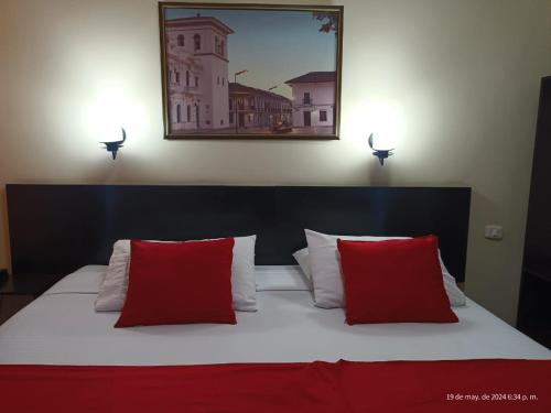 a bedroom with a bed with two red pillows at Hotel La Herreria Colonial in Popayan