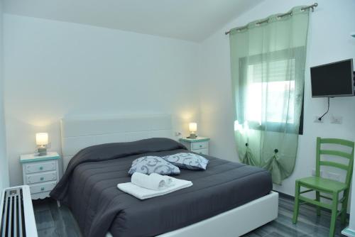 a bedroom with a bed and a television and a chair at Rosa dei Venti ROOMS in Abbasanta