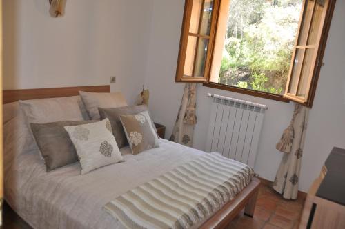 sypialnia z łóżkiem z poduszkami i oknem w obiekcie Domaine la Garenne w mieście Saint-Marc-Jaumegarde