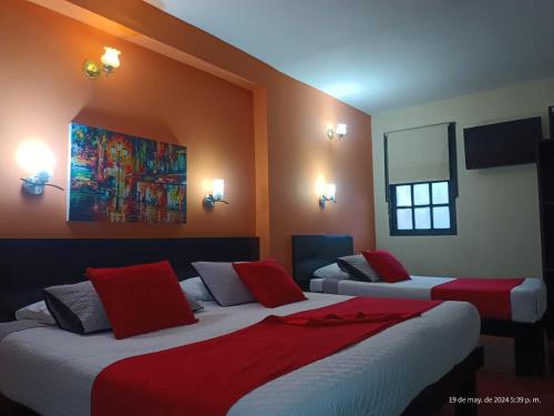 a bedroom with two beds with red and white sheets at Hotel La Herreria Colonial in Popayan
