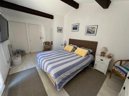a bedroom with a bed with a blue and white striped blanket at Bel appartement - 2 chambres- bord de plage- vue mer-climatisé in Bormes-les-Mimosas