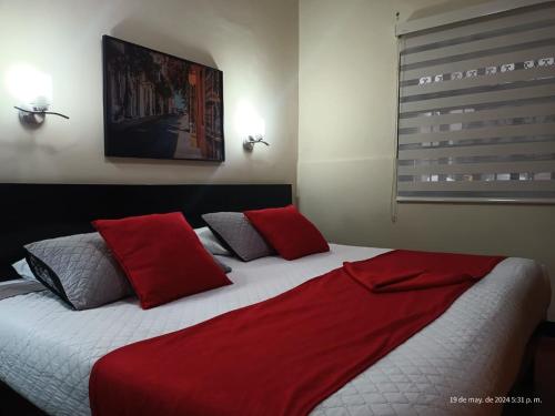 a bedroom with a large bed with red pillows at Hotel La Herreria Colonial in Popayan