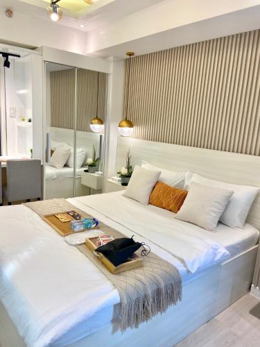 Una gran cama blanca con una bandeja encima. en Alexis Place Azure North, en San Fernando