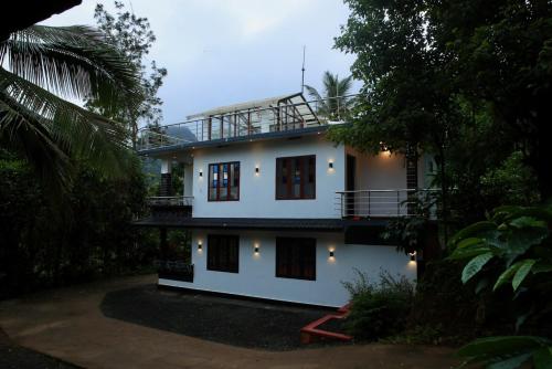 Casa blanca con balcón en la parte superior. en Shivas Farmhouse, en Sultan Bathery