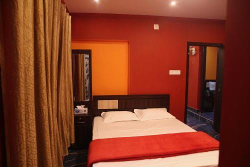 1 dormitorio con 1 cama con pared roja en Shivas Farmhouse, en Sultan Bathery