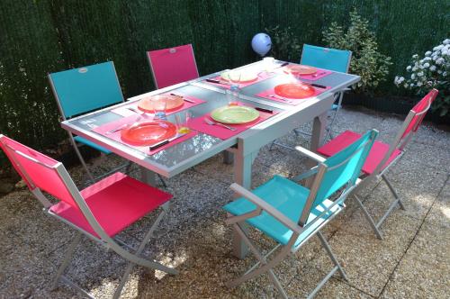 une table avec des chaises, des assiettes et des verres à vin dans l'établissement maisonnette saint georges de didonne, à Saint-Georges-de-Didonne