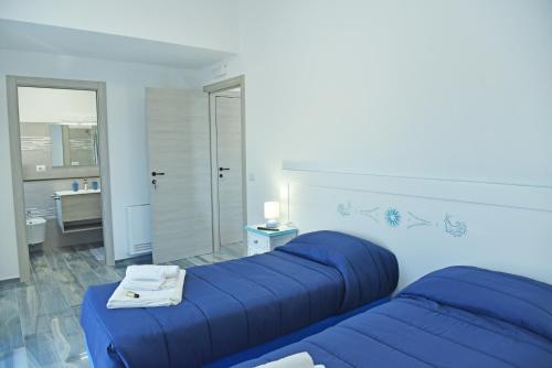 a bedroom with a blue bed and a bathroom at Rosa dei Venti ROOMS in Abbasanta