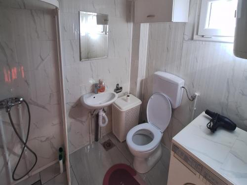 a white bathroom with a toilet and a sink at Fly & Stay Apartments in Laktaši