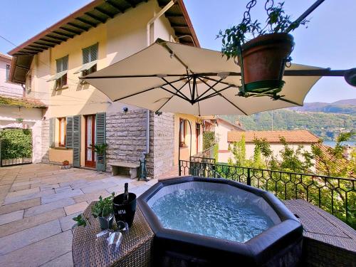 a hot tub on a patio with an umbrella at Casa Gelsomino, Laglio, Lake Como in Laglio