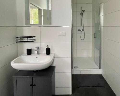 a white bathroom with a sink and a shower at Ferienwohnungen am Park in Wilhelmshaven