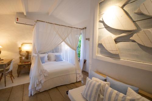 a bedroom with a white bed and a window at Santa Fe Casas Hotel Trancoso in Trancoso