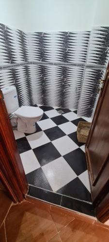 a bathroom with a toilet and a checkered floor at Page et montagne chez Ben&Edd in Ksar es Sghir
