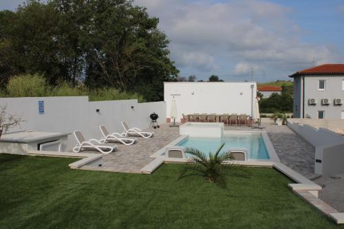 um quintal com uma piscina com cadeiras ao lado de um edifício em Holiday House emjalemi em Pula