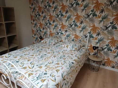 un letto in una camera da letto con carta da parati floreale di Charmante maison en pierres a Sainte-Radégonde-des-Noyers