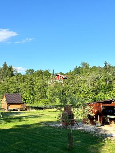 uma vista para um campo com um celeiro e árvores em Green River - robinzonski kamp em Duga Resa