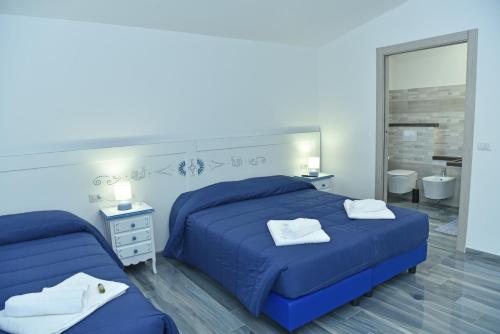 a blue bedroom with two beds and a mirror at Rosa dei Venti ROOMS in Abbasanta