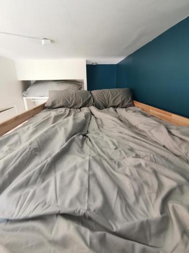 - un lit non aménagé dans une chambre dotée d'un mur bleu dans l'établissement Studio cozy - Proche Paris, Métro, salles de concert et Disneyland, à Montreuil