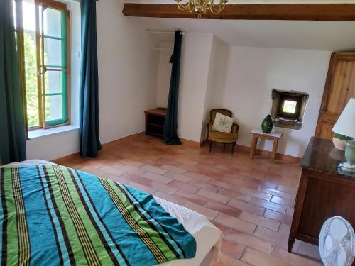 a bedroom with a bed and a table and a chair at La Magnanerie du Berguier in Laurac-en-Vivarais