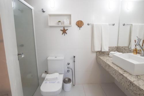 a white bathroom with a toilet and a sink at Hotel VillaReal Guaratuba - Caieiras in Guaratuba