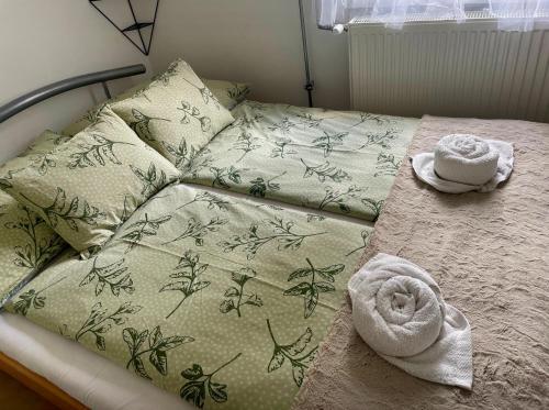 a bed with two pillows and towels on it at Bükk Apartman Bükkszentkereszt in Bükkszentkereszt