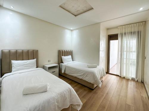 een slaapkamer met 2 bedden en een raam bij Appartement de luxe au Parc au centre pres de la plage in Mohammedia
