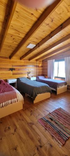 three beds in a room with wooden ceilings at Cabaña los ciruelos in Santa Rosa de Calamuchita