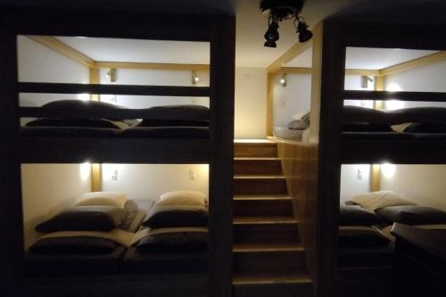 a room with three bunk beds and a staircase at Bivouac & Sacs à dos - Loft classé, avec escape game sur demande in Sixt