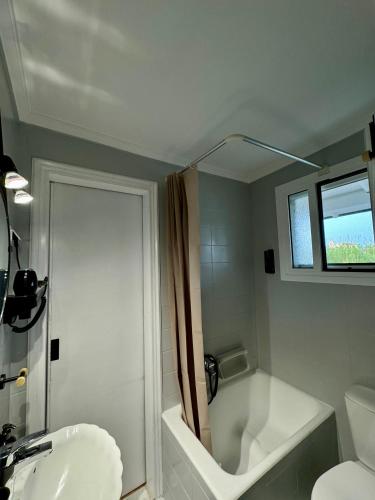 a bathroom with a tub and a toilet and a sink at Captain Christos Family Garden House in Lefkimmi