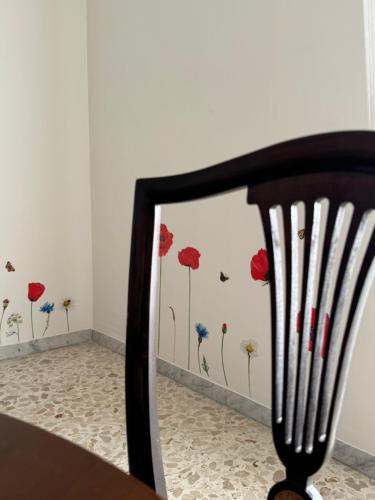 a chair in front of a wall with red and blue flowers at L'Antica dimora in Terlizzi