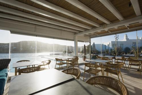 un restaurante con mesas, sillas y ventanas grandes en Mykonos Pantheon, en Playa Kalo Livadi