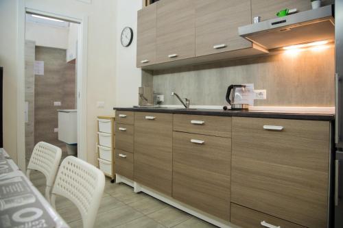 eine Küche mit Holzschränken und weißen Stühlen in der Unterkunft Antico Lamione in Matera