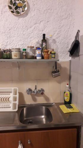 a kitchen counter with a sink and a shelf above it at Πέτρινο σπίτι-Stone house in Koíta