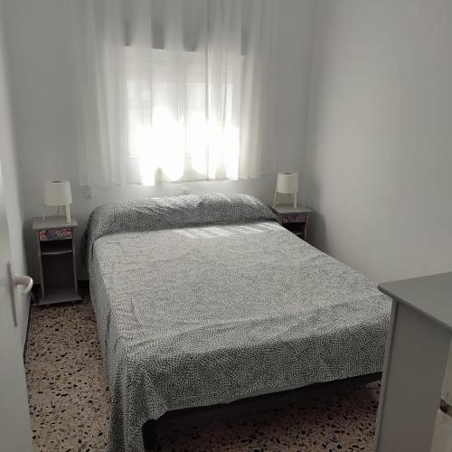a bedroom with a bed with two night stands and a window at Duplex en centro de Chipiona in Chipiona