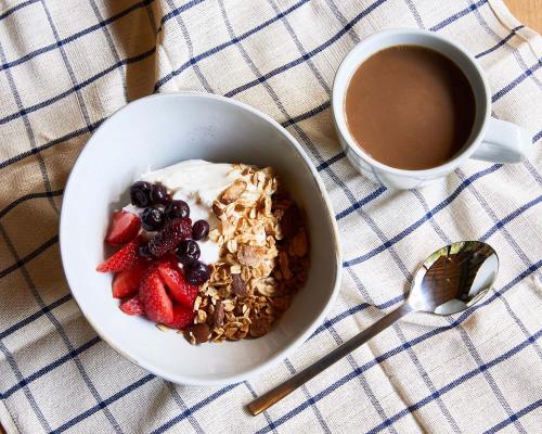 una ciotola di granola e frutti di bosco accanto a una tazza di caffè di AutoCamp Asheville ad Asheville