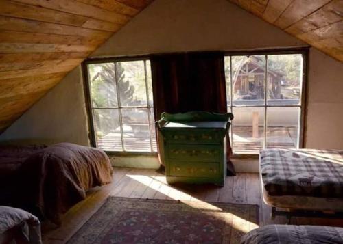 a attic room with two beds and two windows at Rancho Callado - Kumiai Cabin in Rinconada