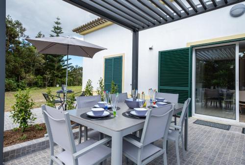 een tafel met stoelen en een parasol op een patio bij Estalagem Pico D'Agua in Livramento