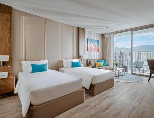 two beds in a hotel room with a view at Panorama Nha Trang SanVilla in Nha Trang